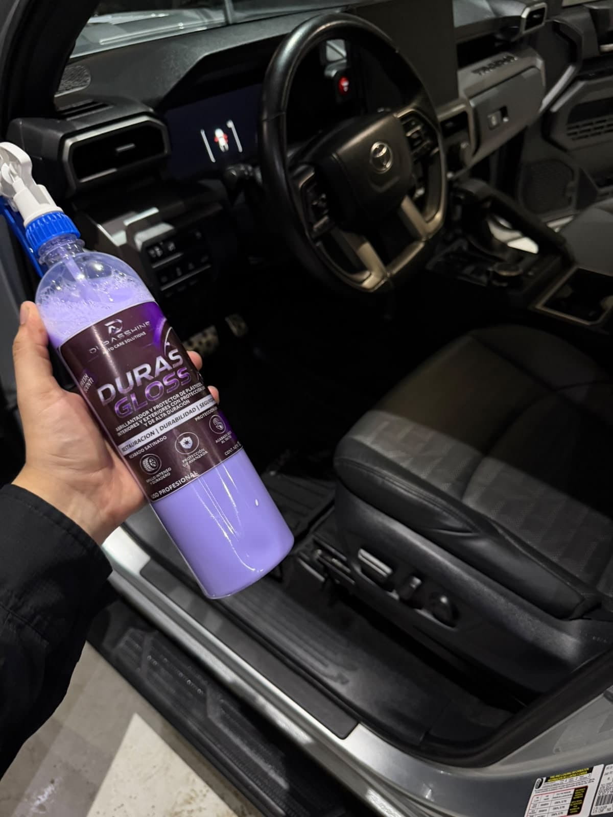 Duras Gloss en la mano dentro de una camioneta, junto al tablero